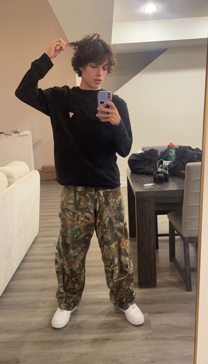 a young man taking a selfie with his cell phone in front of the mirror