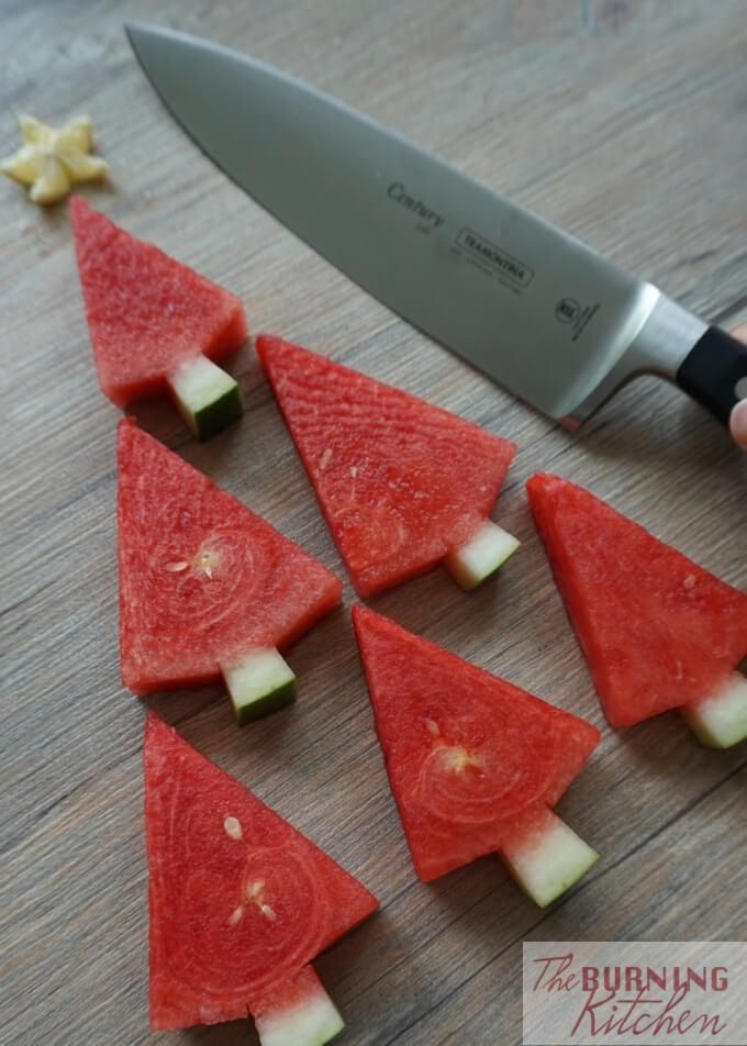 someone is cutting up slices of watermelon on a wooden table with a knife