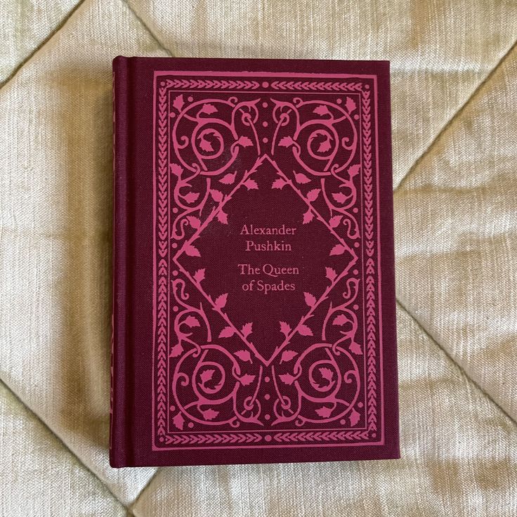 a red book sitting on top of a bed next to a white wall and floor