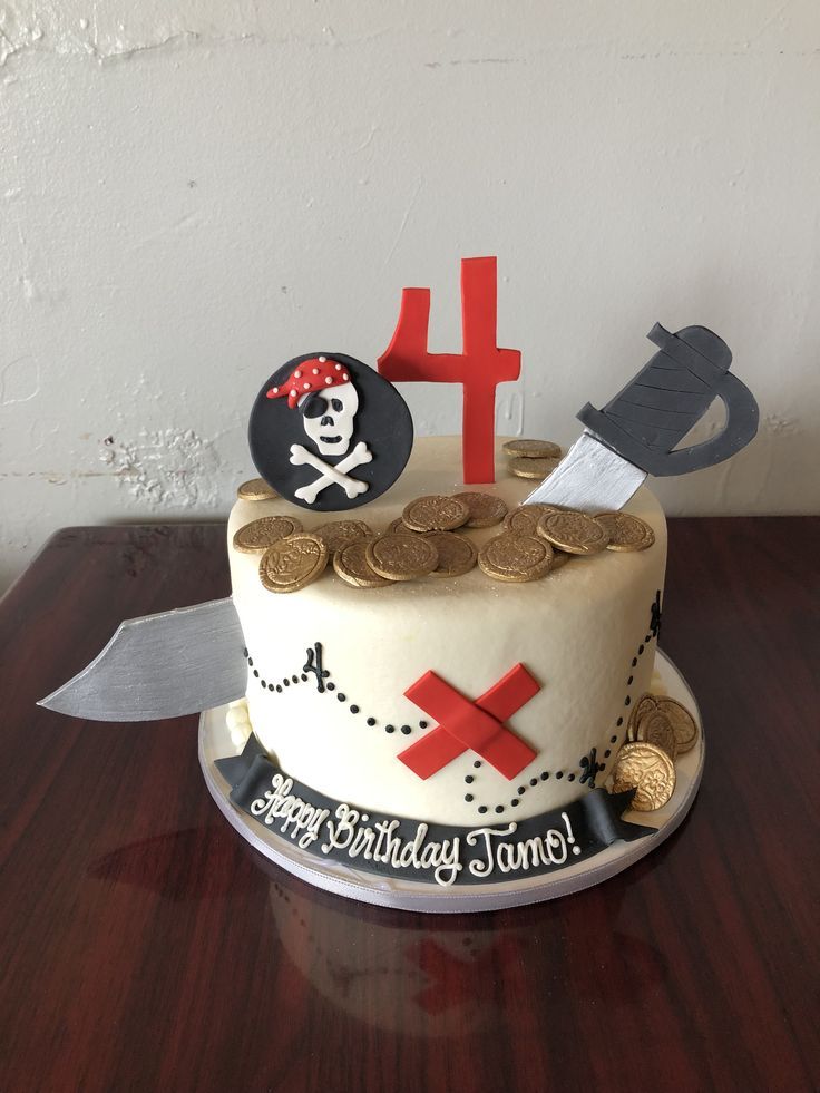 a pirate themed birthday cake with coins and a knife on the table next to it