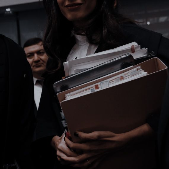 a woman holding files and folders in her hands while standing next to other people