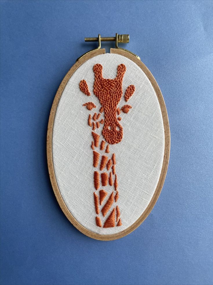 a close up of a embroidery on a hoop with a giraffe head in the middle