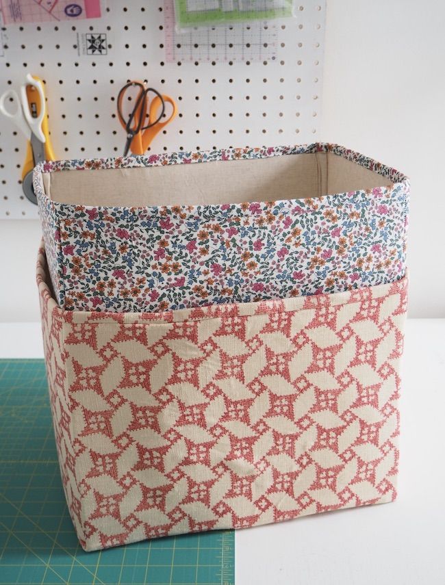 a pair of scissors are sitting in a storage bin on a table next to some crafting supplies