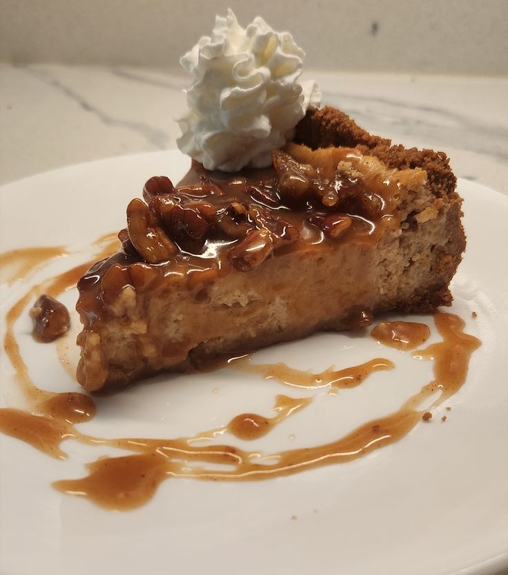 a piece of pie on a white plate with caramel drizzle and whipped cream