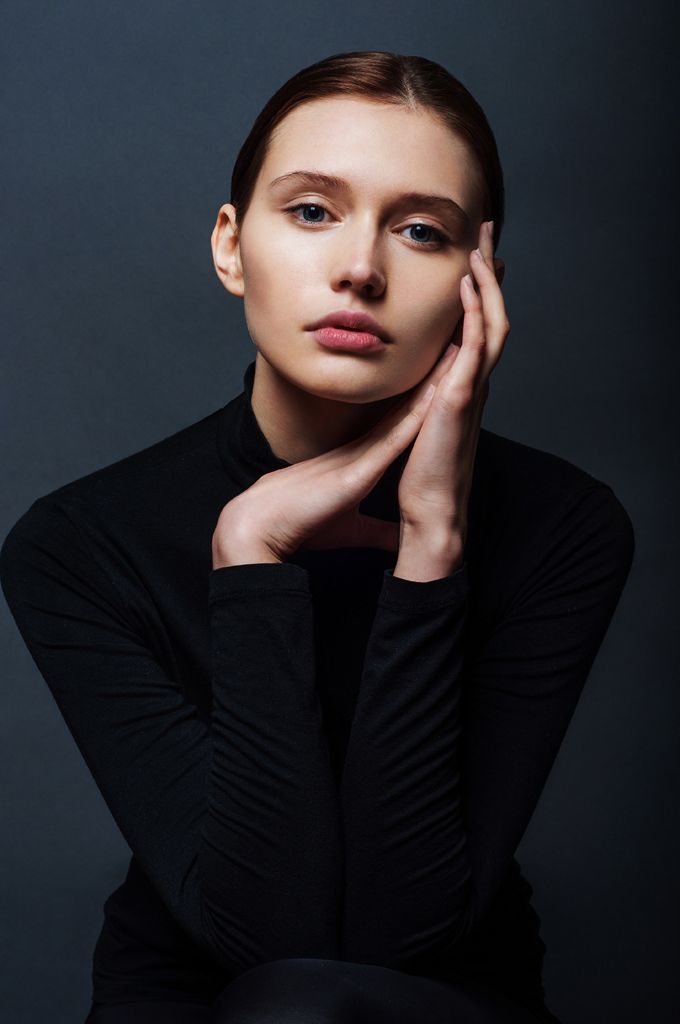 a woman with her hand on her chin, posing for the camera and looking at the camera