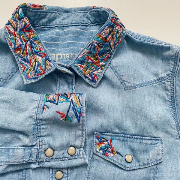 a blue jean jacket with multicolored sequins on the collar