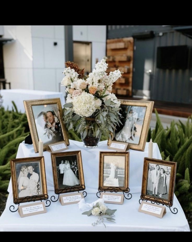 a table topped with pictures and flowers on top of a white cloth covered tablecloth