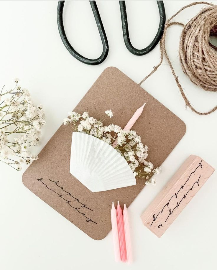 some crafting supplies are laid out on a table with twine, scissors and flowers