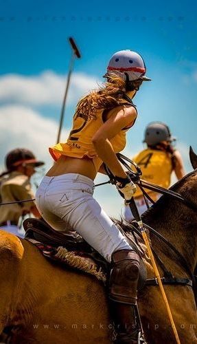 a woman riding on the back of a brown horse next to another person wearing a helmet