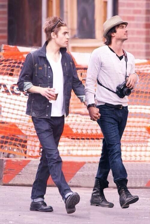 two young men walking down the street with construction cones in the back ground behind them