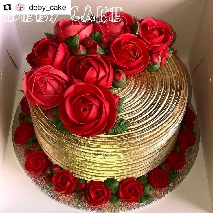 there is a cake with red roses on the top and gold icing around it