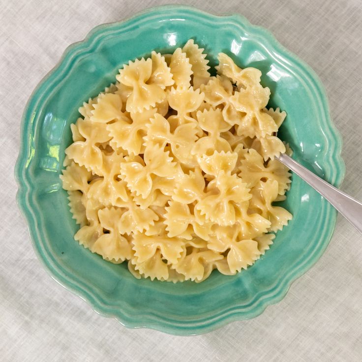 a green bowl filled with macaroni and cheese on top of a white table