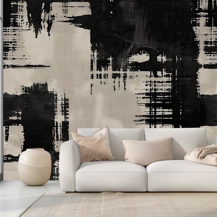 a white couch sitting in front of a wall with black and grey paint on it