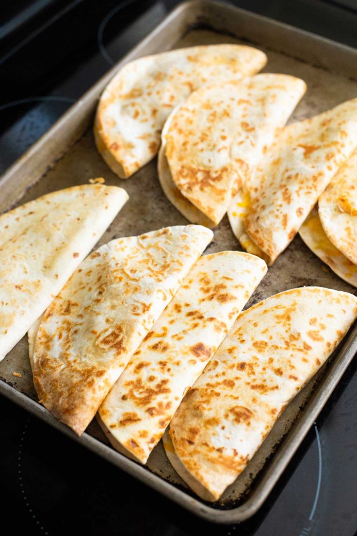 several quesadillas on a baking sheet ready to be cooked in the oven