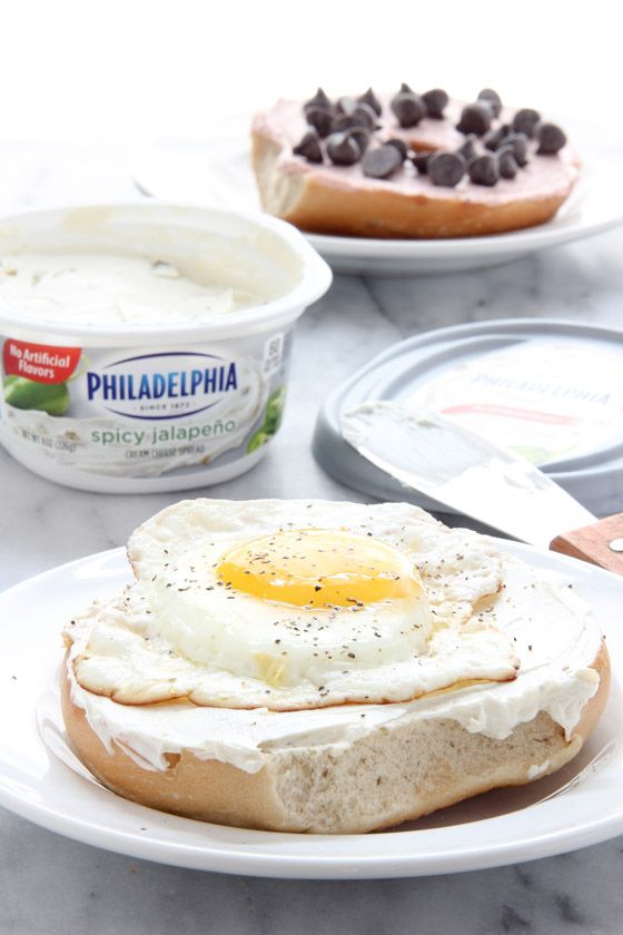 an egg on top of a bagel with chocolate chips and yogurt in the background