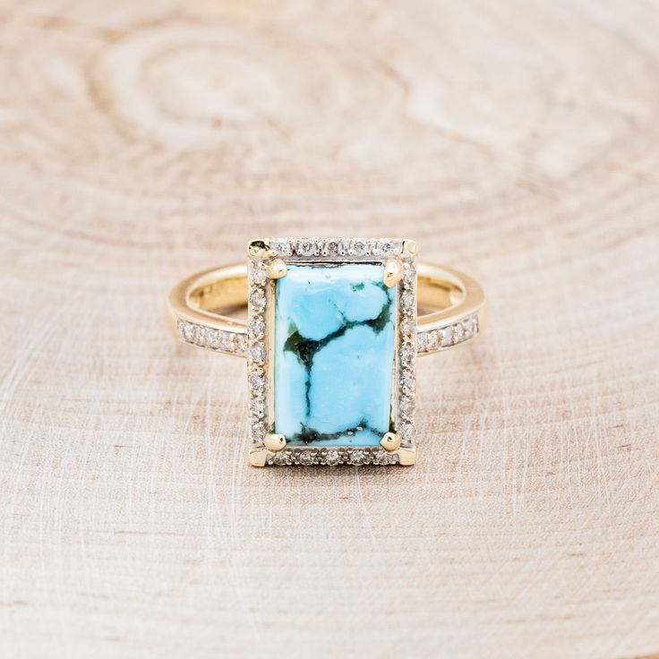 a gold ring with a blue stone surrounded by white and yellow diamonds on a wooden surface