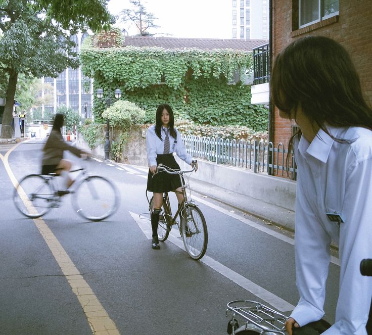 two women riding bicycles down the street