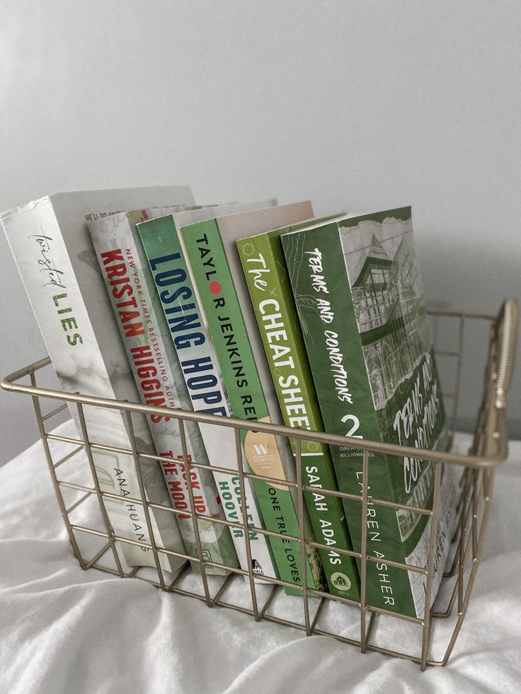 a metal basket filled with books on top of a bed