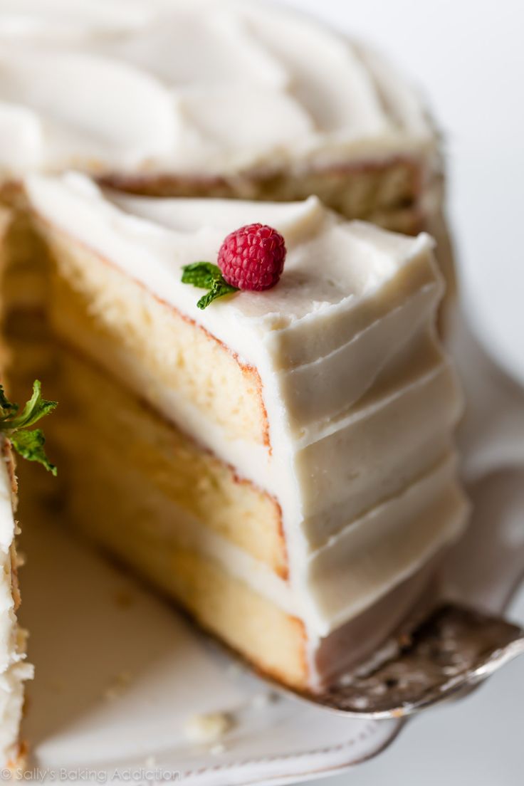 a cake with white frosting and a raspberry on top is cut in half