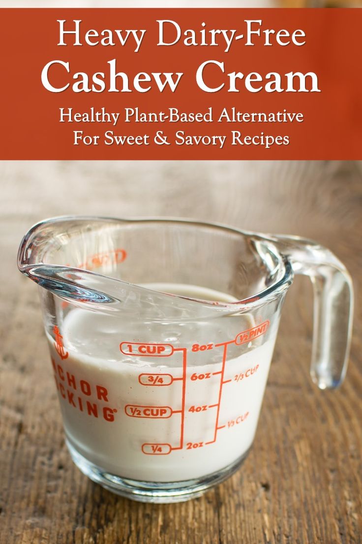 a glass measuring cup filled with milk on top of a wooden table and text overlay reads heavy dairy - free cashew cream healthy plant - based alternative for sweet & savor