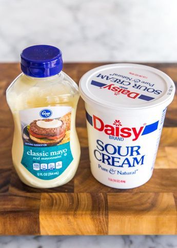 two yogurt containers sitting on top of a wooden cutting board