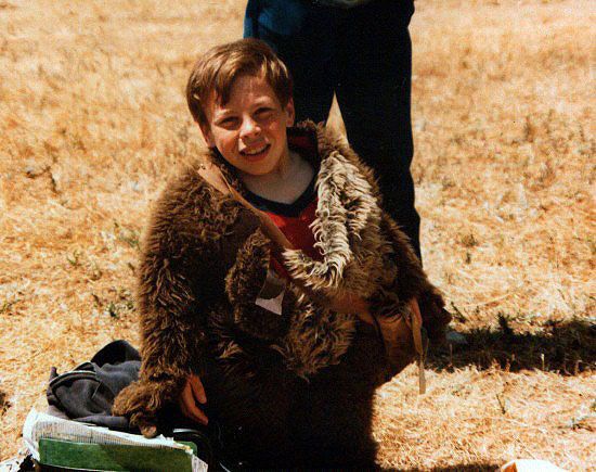 a young boy sitting on the ground next to a teddy bear