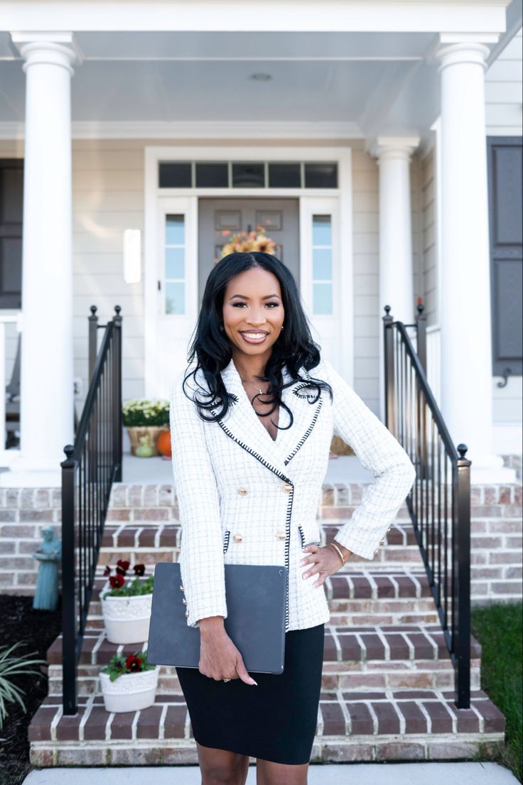 a woman standing in front of a house with her hands on her hips and smiling