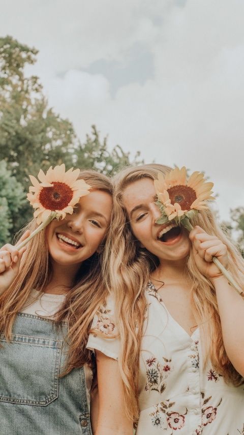 two girls with sunflowers on their heads are posing for the camera and smiling