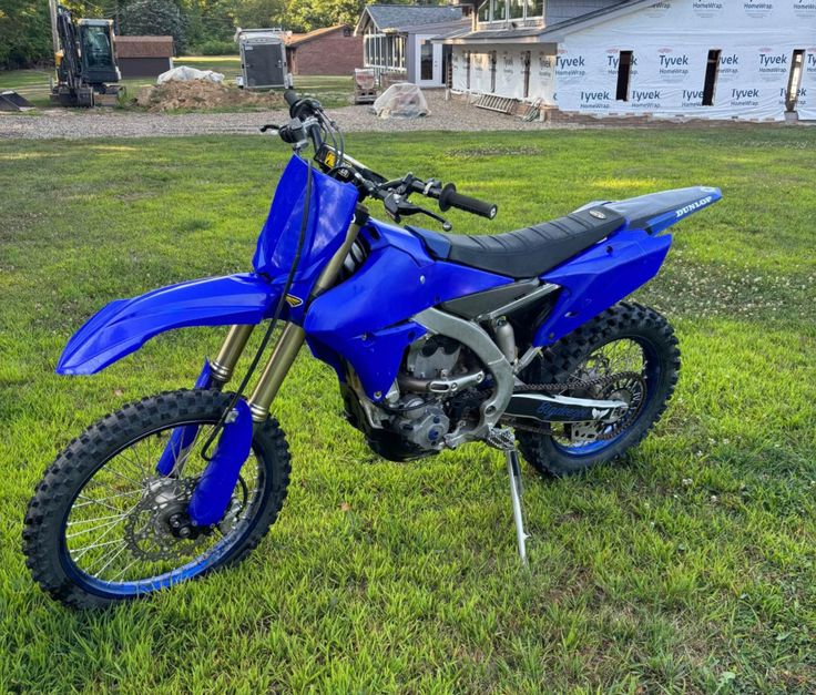 a blue dirt bike parked in the grass