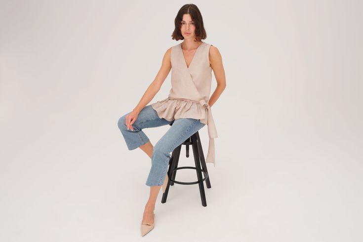 "Leola" Blouse is a V Neck top with a peplum ruffle on the bottom and an elegant side belt bow that can be adjusted. Classic Fit. Material: 55% Linen 45% Tencel. Model wears size 'S'. Care: Dry Clean or Machine Wash Cold/Lay Flat To Dry. Chic Peplum Top For Day Out, Chic Peplum Blouse For Work, Chic Belted V-neck Top, Chic Peplum Workwear Blouse, Feminine Peplum Blouse For Work, Chic Peplum Top With Ruffle Hem For Fall, Chic Fall Peplum Top With Ruffle Hem, Chic Summer Workwear Peplum Top, Peplum Blouse With Ruffles For Work