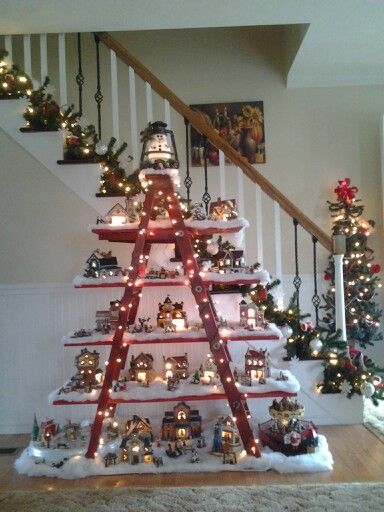 a christmas tree with lights on it in the middle of a stair case next to a banister