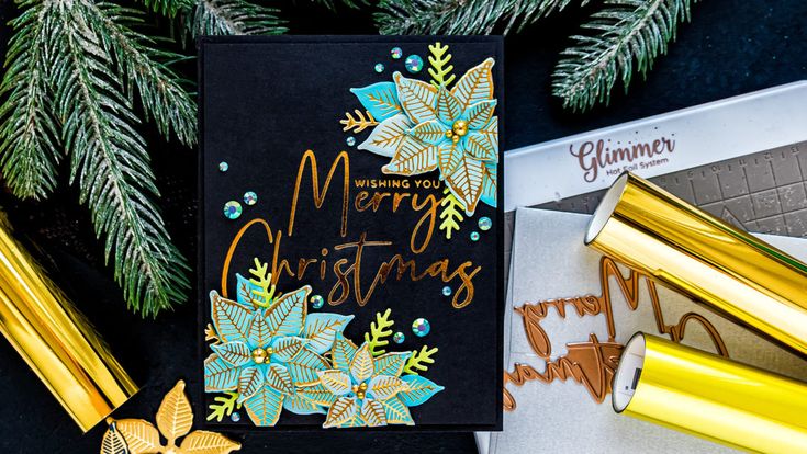 a christmas card with gold foil on it next to other holiday decorations and wrapping paper