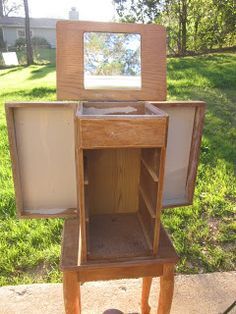 a small wooden cabinet sitting on top of a cement slab next to a grass covered yard