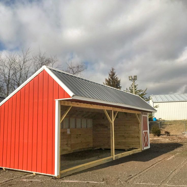 a red barn sitting in the middle of a parking lot