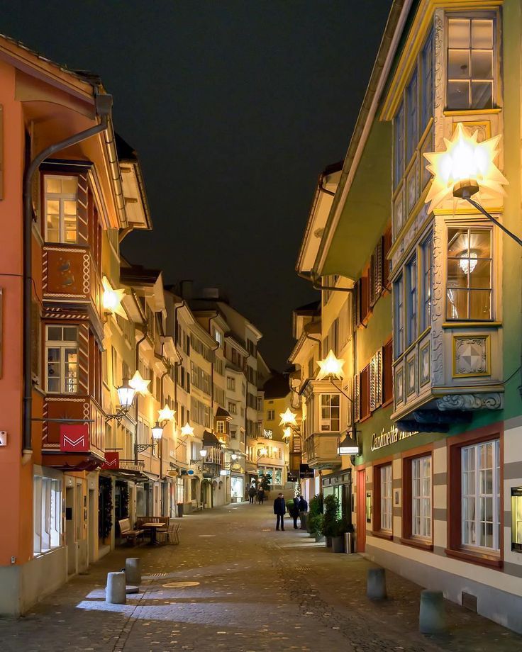 an empty street at night with people walking down it