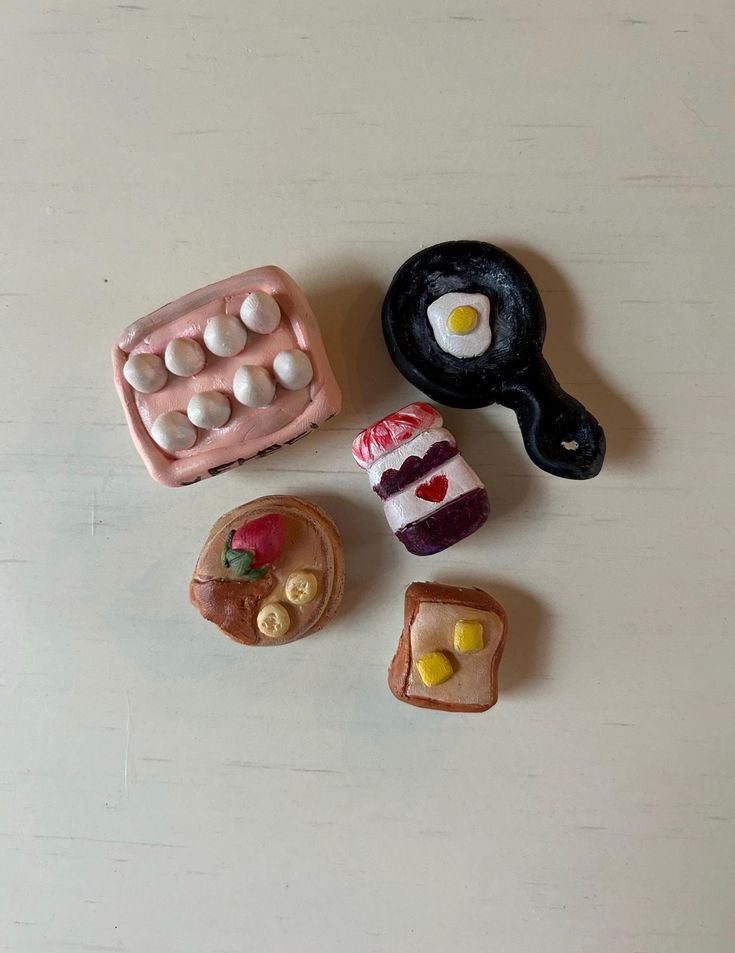 small toy food items are arranged on a table top, including an egg and toaster