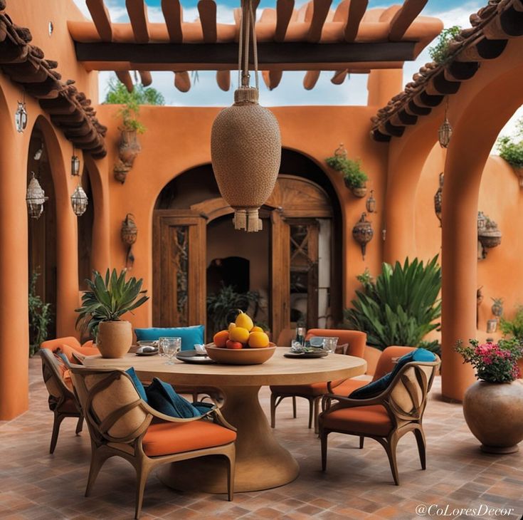 an outdoor dining area with orange walls and potted plants on the table, surrounded by chairs