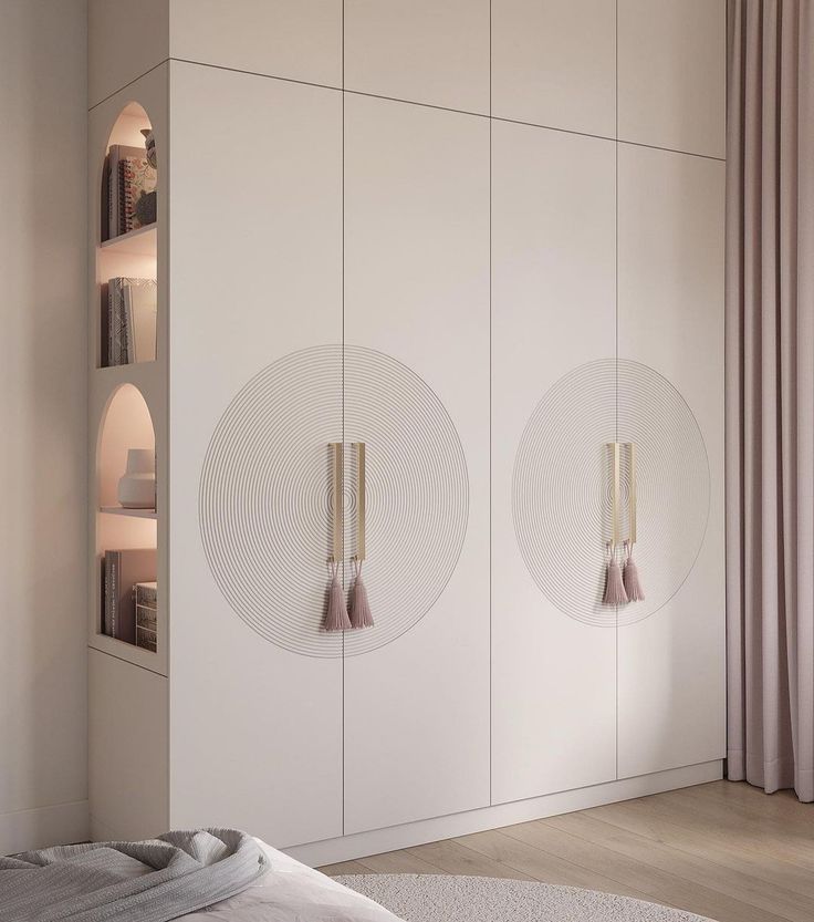 a bedroom with white cupboards and two round mirrors on the wall next to a bed