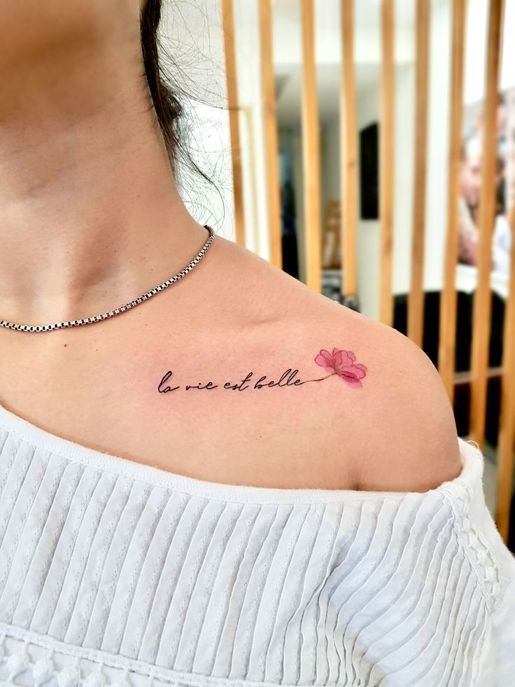 a woman's chest with the word love and two flowers on her left shoulder