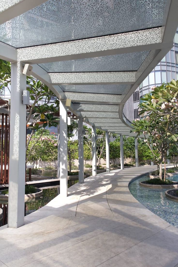 the walkway is lined with white pillars and water features at each end, along with trees and bushes