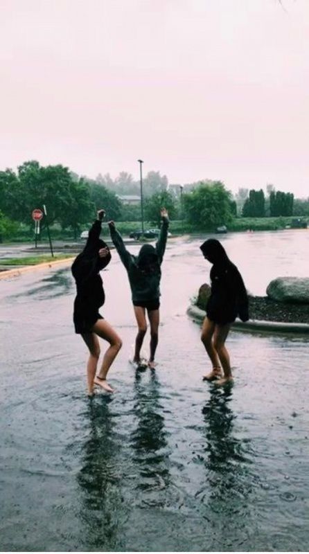 three people standing in the middle of a flooded street with their hands up and arms raised