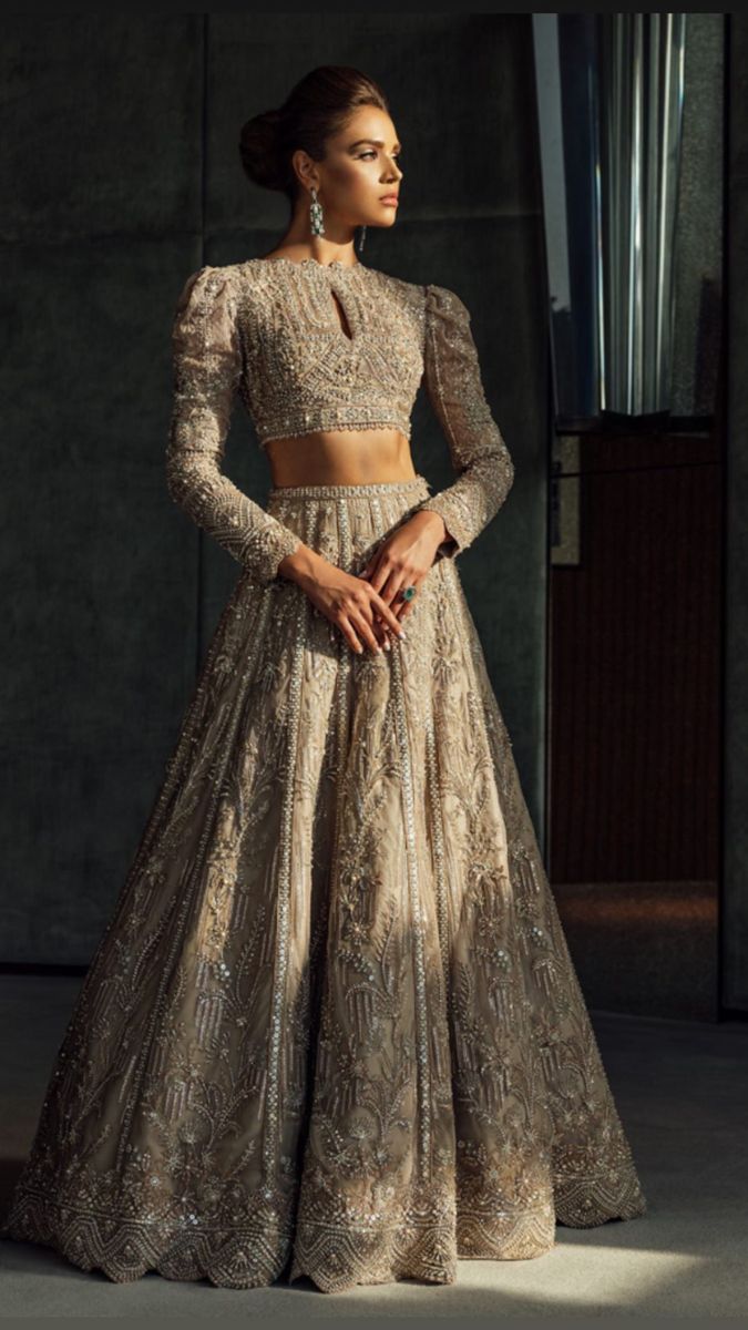 a model walks the ramp in a beige lehenga with matching blouse and dupatta