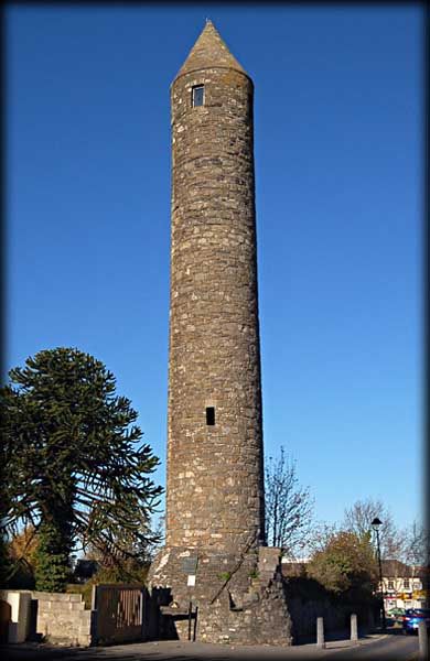 a tall brick tower with a clock on it's side in the middle of a street