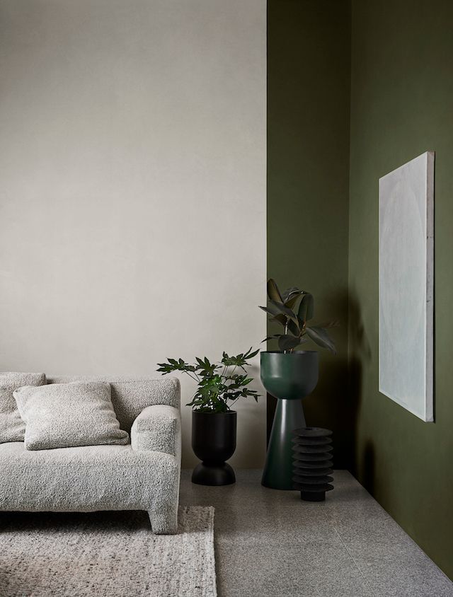 a white couch sitting next to a tall plant in a living room on top of a hard wood floor