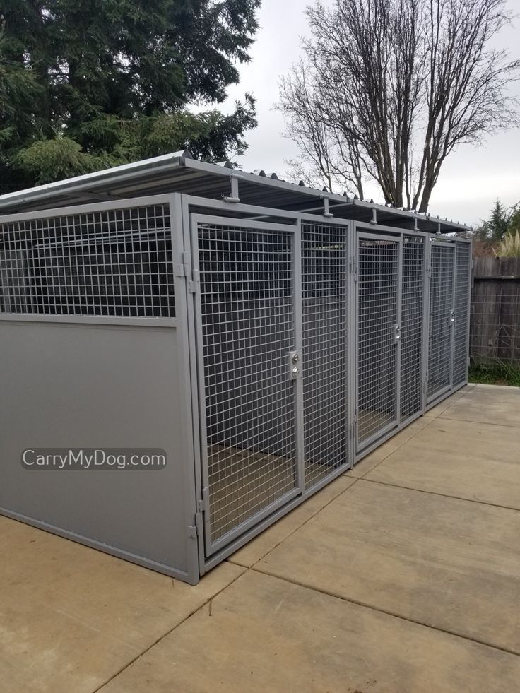 an outdoor dog kennel in the middle of a driveway