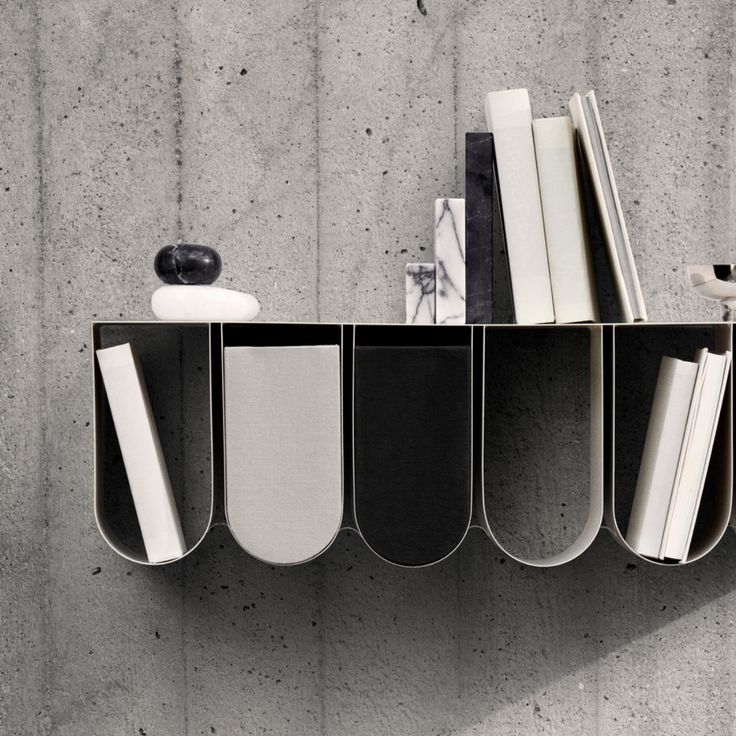 a shelf with books and other items hanging on the wall next to a concrete wall