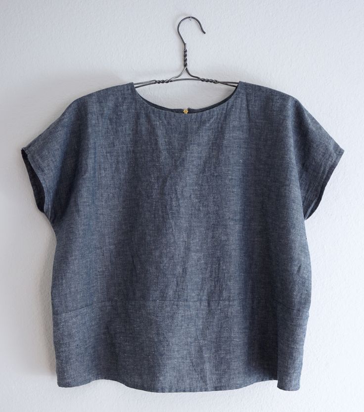 a blue top hanging on a white wall next to a hanger with an object in it