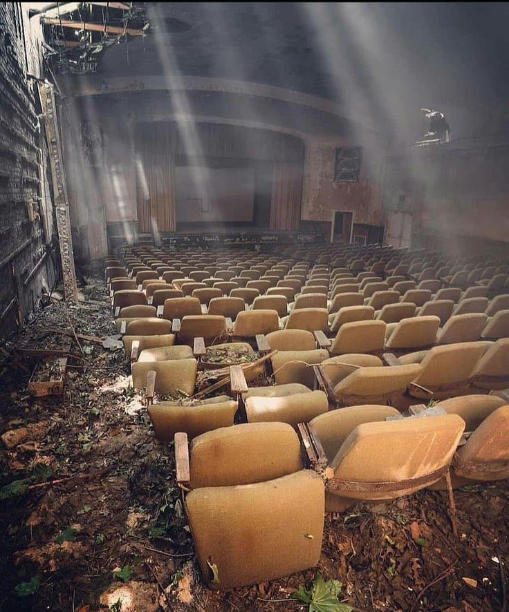 an abandoned auditorium with chairs and lights coming from the ceiling