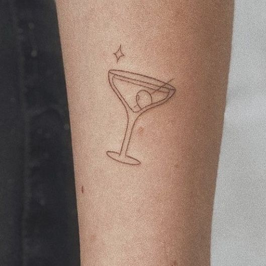 a tattoo on the arm of a woman with a martini glass in it's center