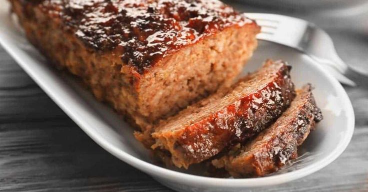 meatloaf on a white plate with a salad in the background